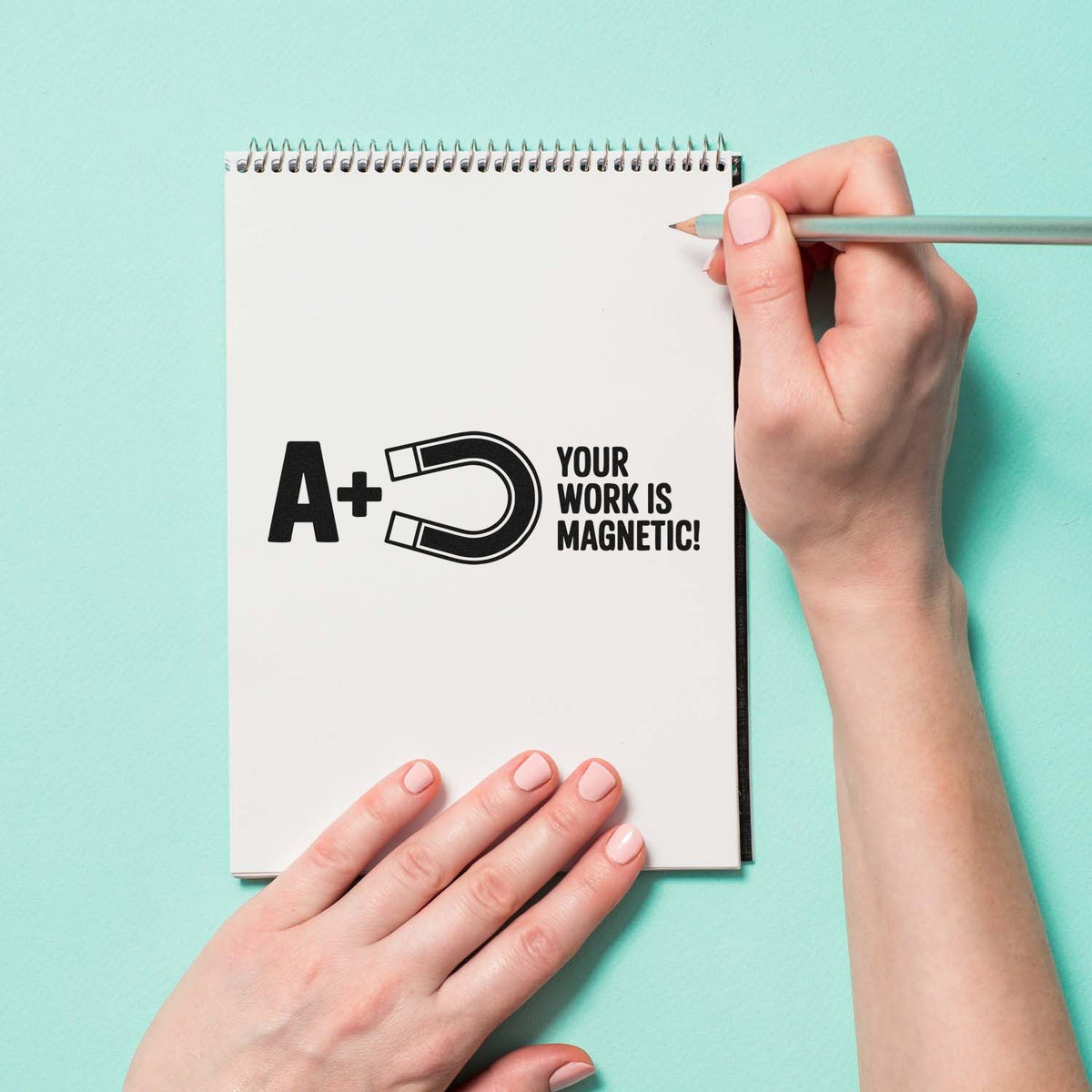 A+ Your Work Is Magnetic teacher rubber stamp design on notebook, ideal for rewarding student work.