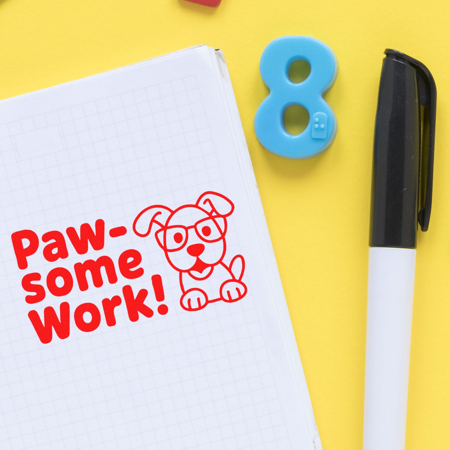 Paw-some Work! dog rubber stamp beside number 8 stamp and marker on notebook for rewarding student work.