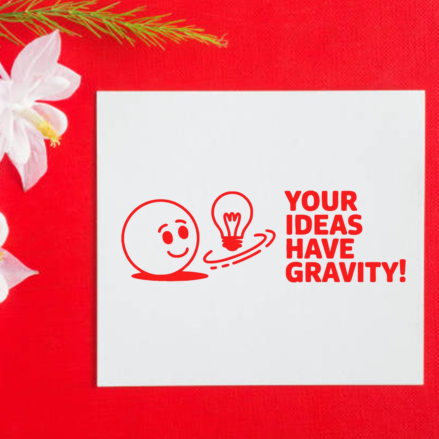 Personalized rubber stamp design with smiling face, lightbulb, and Your Ideas Have Gravity! slogan on white paper.