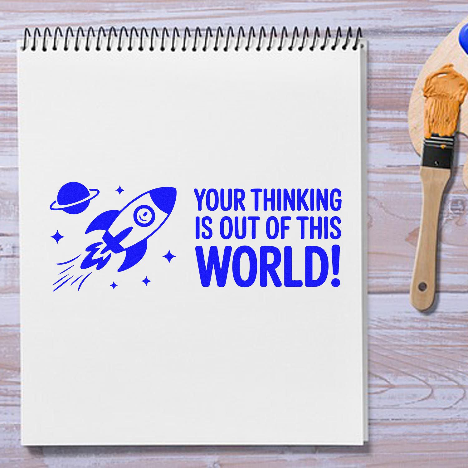 Rubber stamp design with rocket and Your thinking is out of this world! message on a notebook for creative space-themed projects