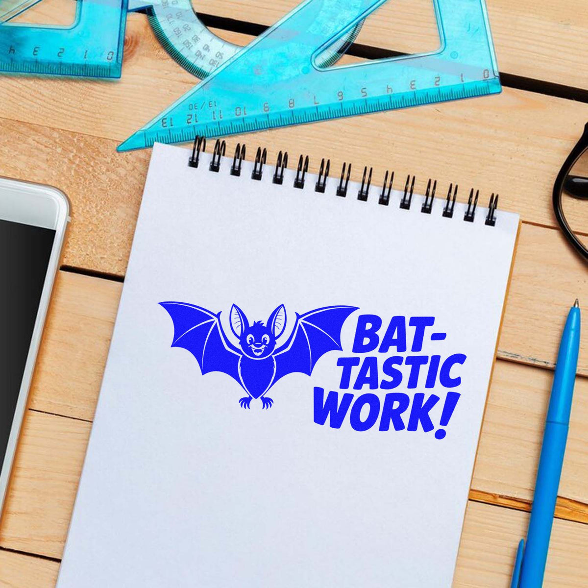 Custom rubber stamp mockup with bat mascot and "Bat-tastic Work!" on notebook, ideal for teacher reward stamps.