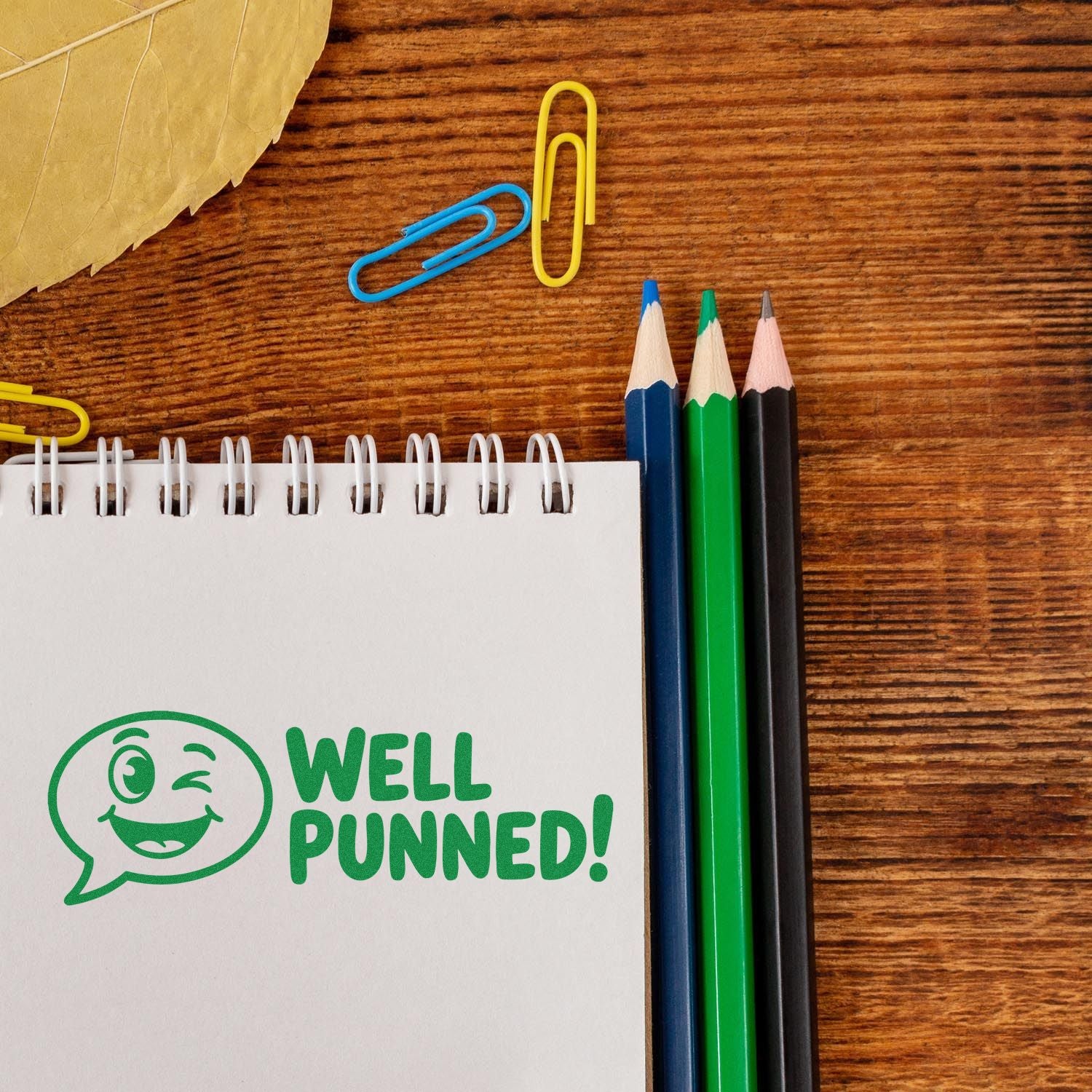 Custom rubber stamp reading Well Punned! on notebook, perfect for playful teacher or office stationery.
