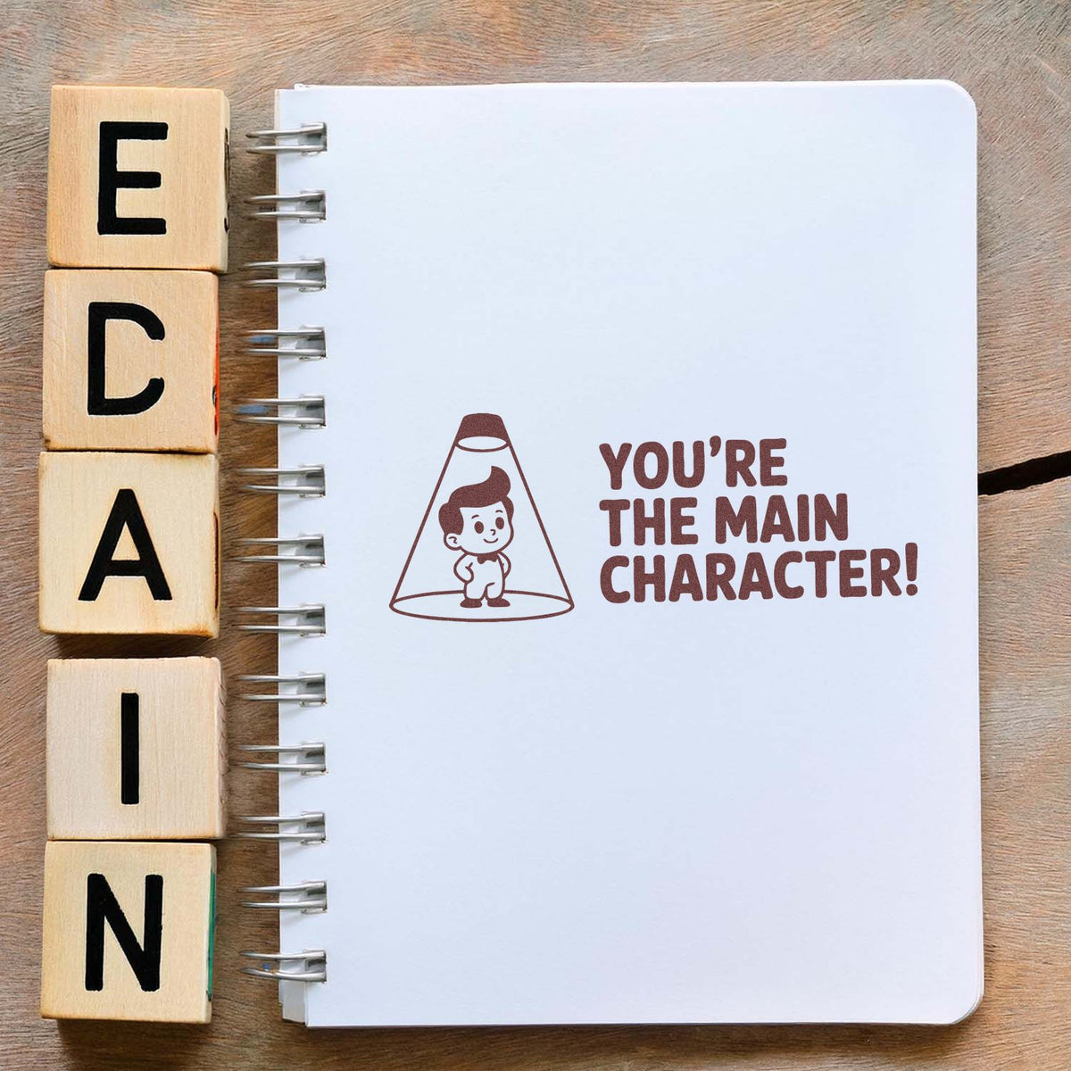 Motivational rubber stamp design reading Youre the Main Character! with cartoon in spotlight for craft journaling.