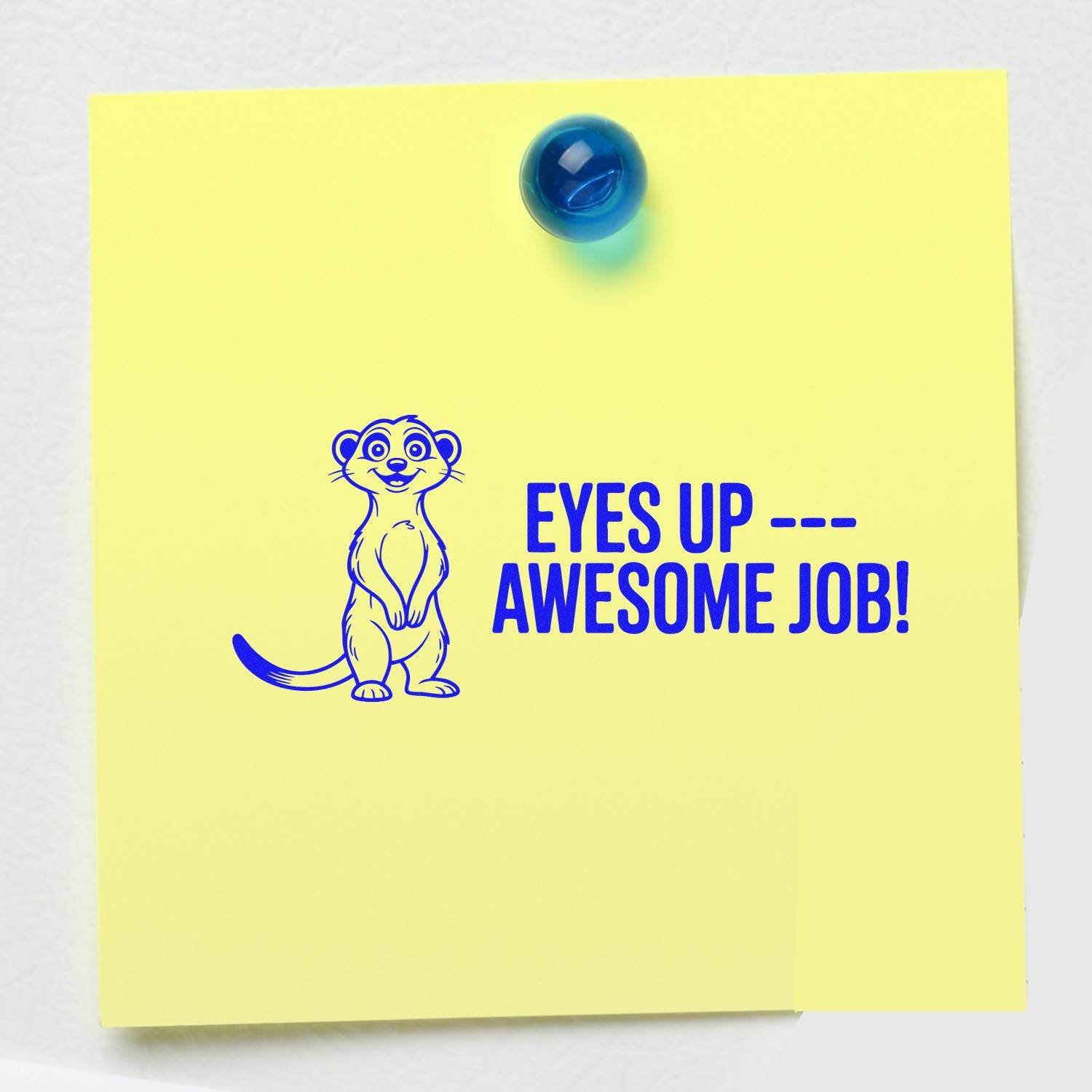 Motivational rubber stamp with meerkat saying Eyes UpAwesome Job! stamped on a yellow sticky note.
