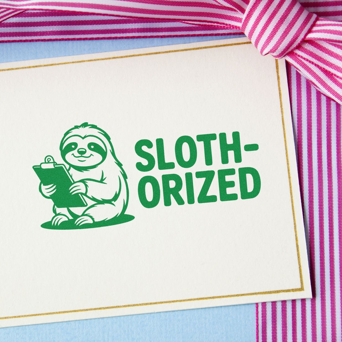 Green sloth-oriz??ed rubber stamp on a greeting card with pink ribbon, ideal for handmade stationery and craft projects.