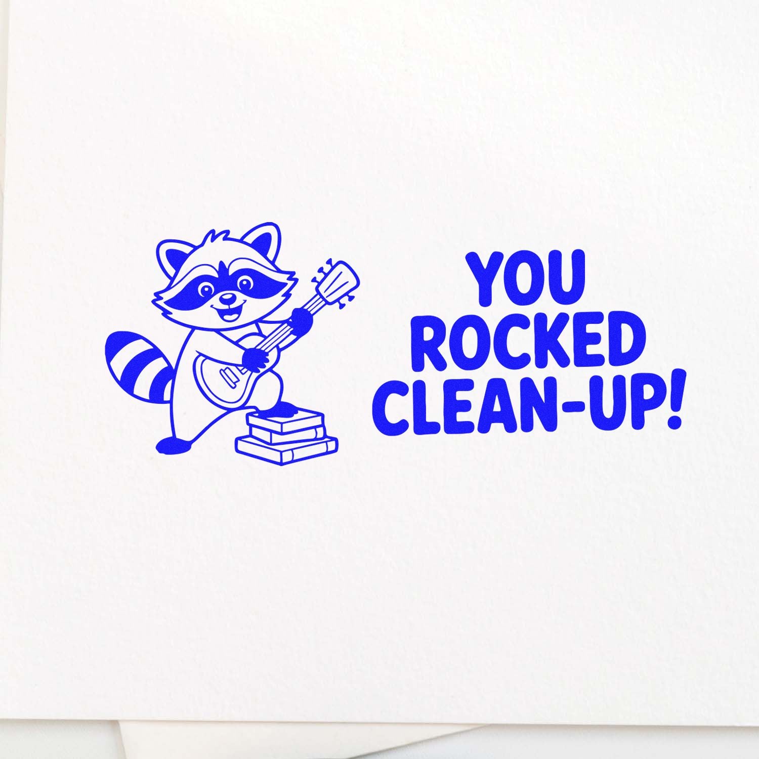 Blue rubber stamp design with raccoon playing guitar and You Rocked Clean-Up! text for kids reward stamps.