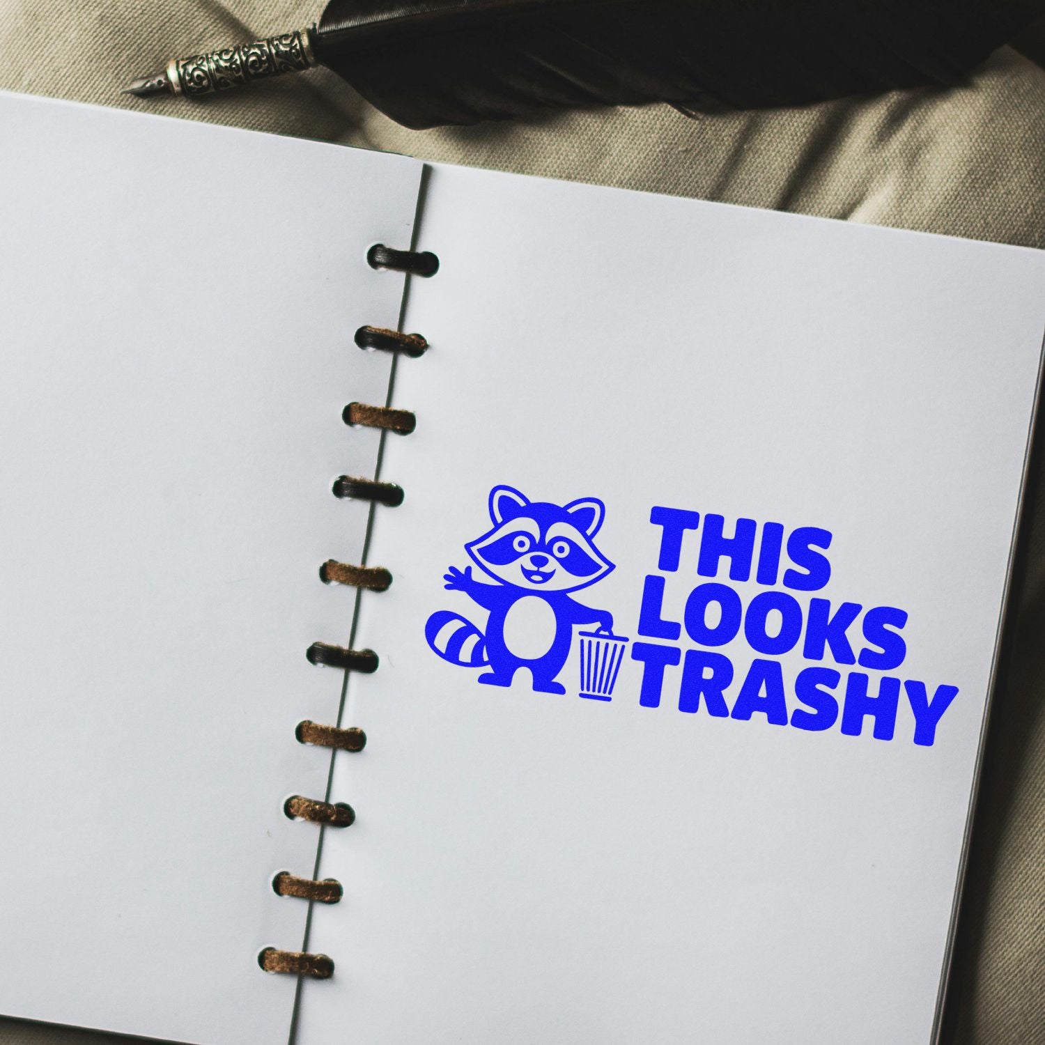 Custom rubber stamp design with raccoon and trash can reading This Looks Trashy on a notebook page.