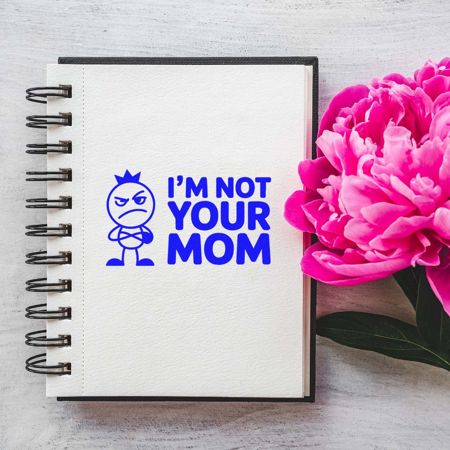 Humorous Im Not Your Mom rubber stamp impression on notebook page with pink flowers.