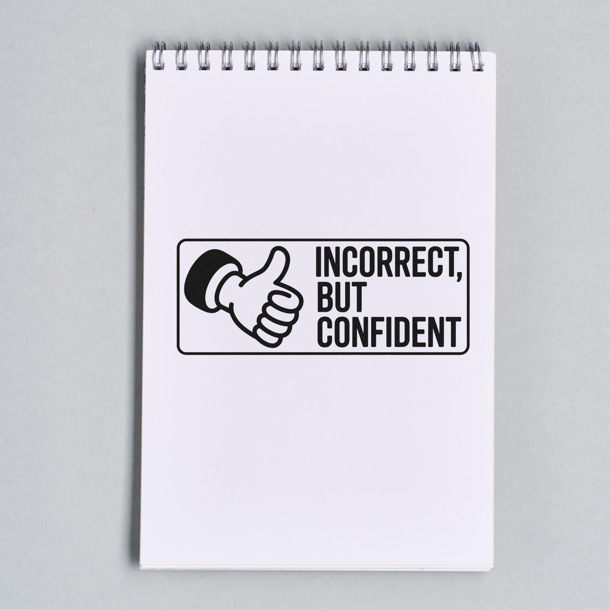 Humorous rubber stamp design on a notepad reading Incorrect, But Confident with thumbs-up icon for office use.