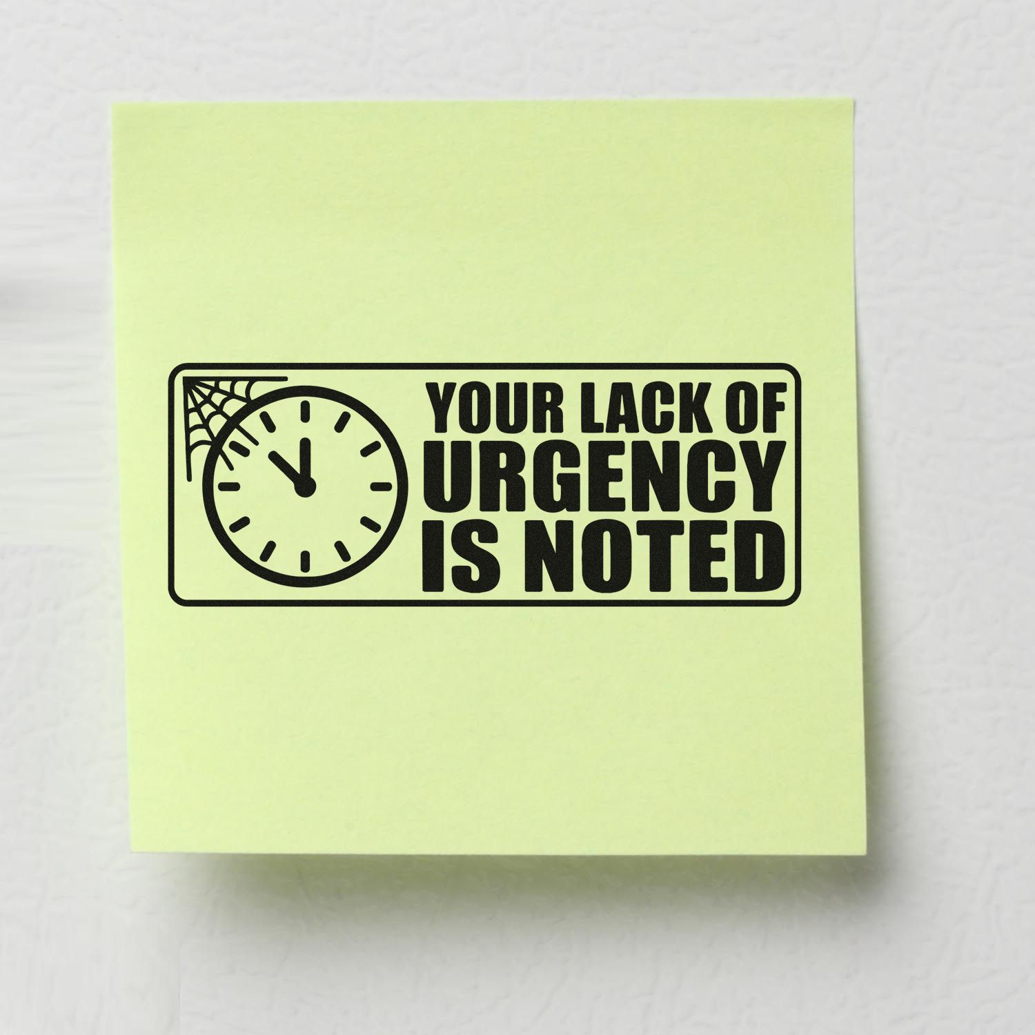 Rubber stamp with clock and spiderweb design reading Your Lack of Urgency Is Noted for office humor and reminders.