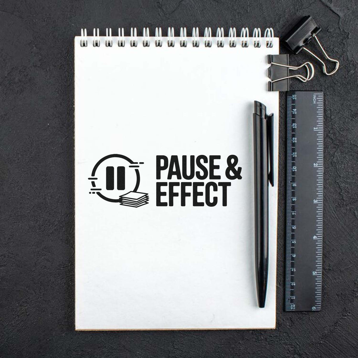 Pause & Effect rubber stamp design on a notebook with pen and ruler, ideal for stationery and office branding.