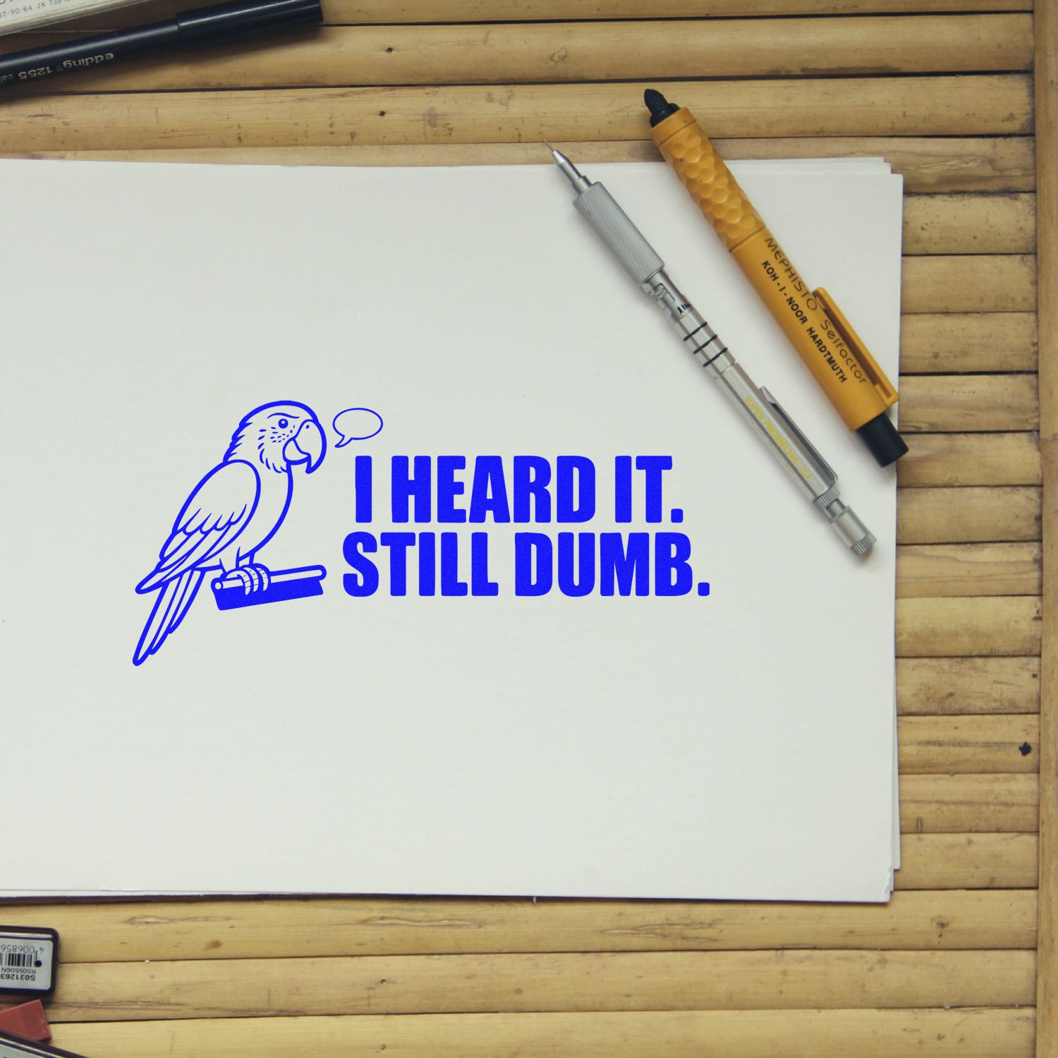 Humorous rubber stamp design with parrot and quote I Heard It. Still Dumb. stamped on paper with drawing tools.
