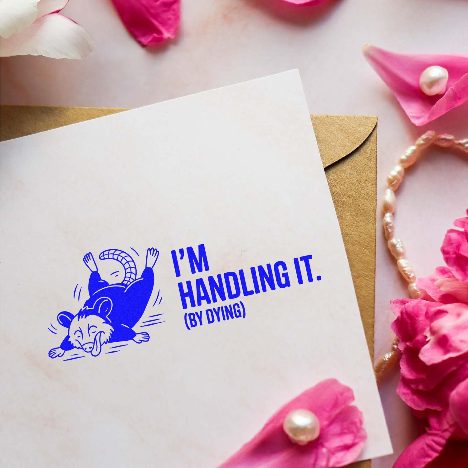 Funny opossum rubber stamp reading Im handling it (by dying) on a blank card with pink floral decor.