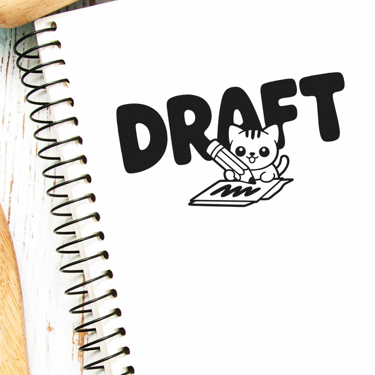 Draft rubber stamp design with cute cat drawing on notebook for marking work-in-progress creative projects.