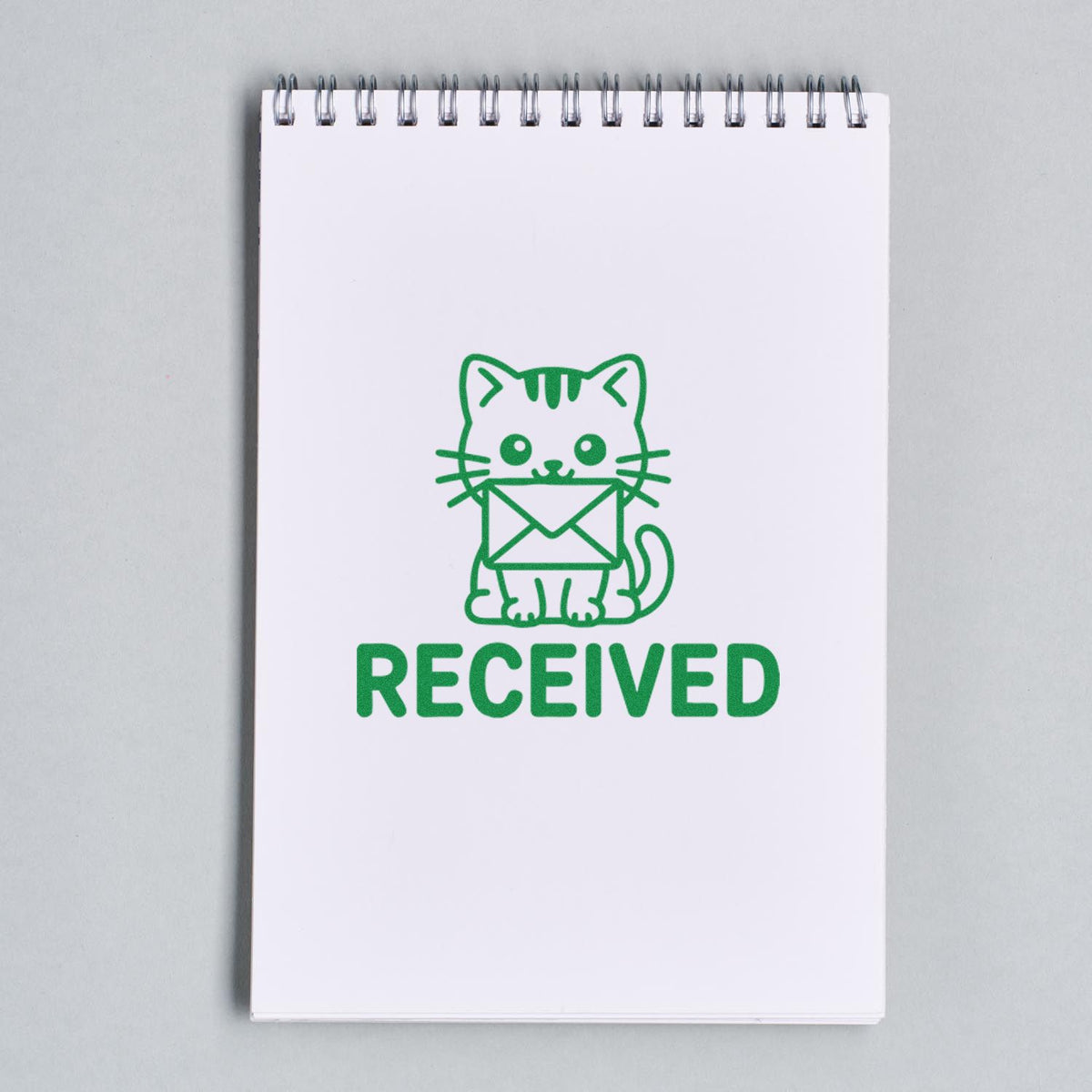 Green cat holding envelope Received rubber stamp on notebook, ideal for office mail processing and custom stamp designs.