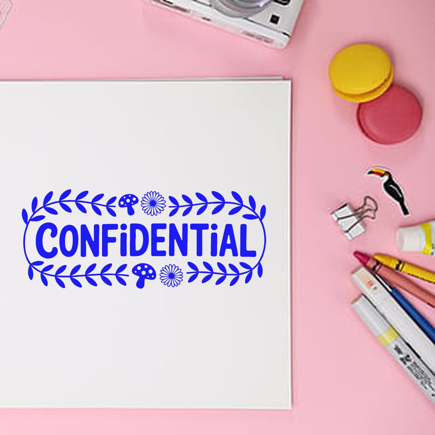 Blue floral confidential rubber stamp on white paper with craft supplies, for document confidentiality and office labeling.