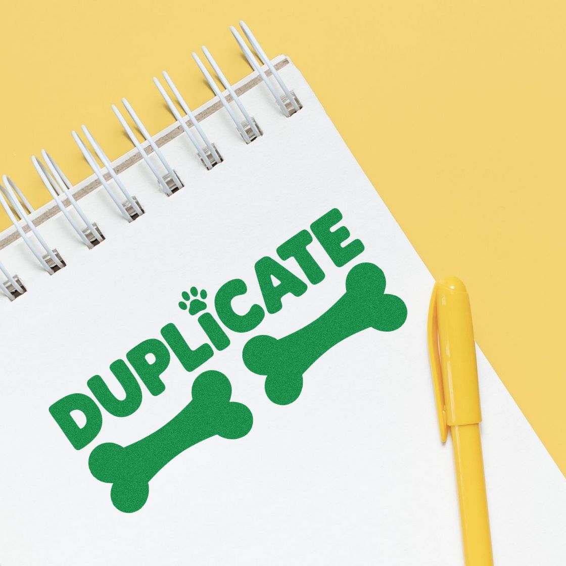 Duplicate rubber stamp graphic on notebook with pen, perfect for office document marking and pet-themed business branding.