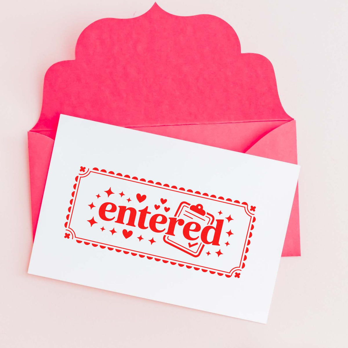 Decorative entered rubber stamp on a card inside a pink envelope, ideal for office mail and document processing.