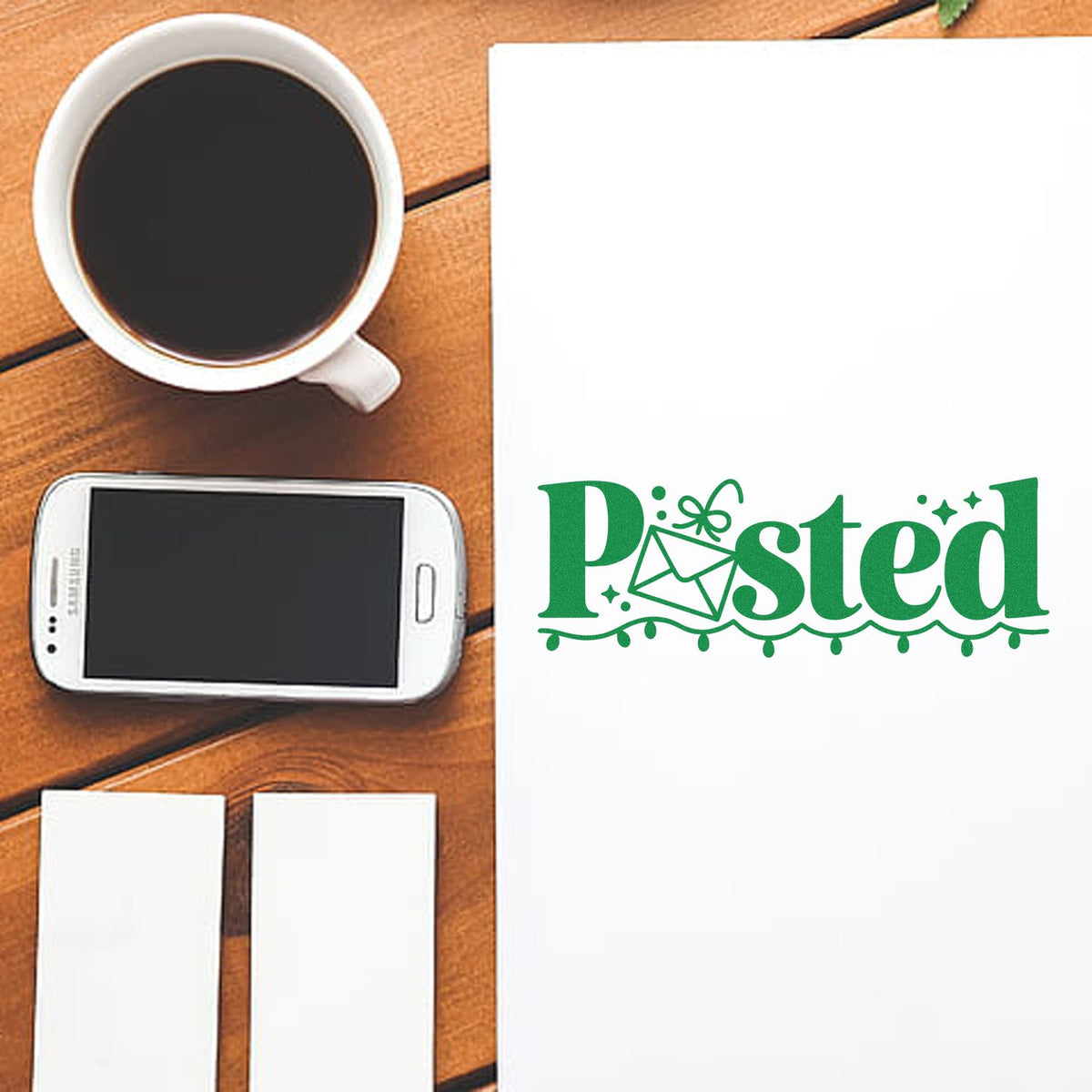 Custom rubber stamp design with green Posted imprint on paper, shown on a desk beside coffee and smartphone.