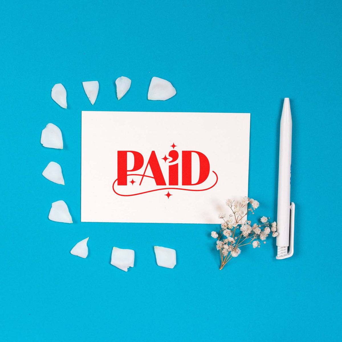 Red PAID rubber stamp design on white card with pen and flowers, ideal for office document approval and bookkeeping.