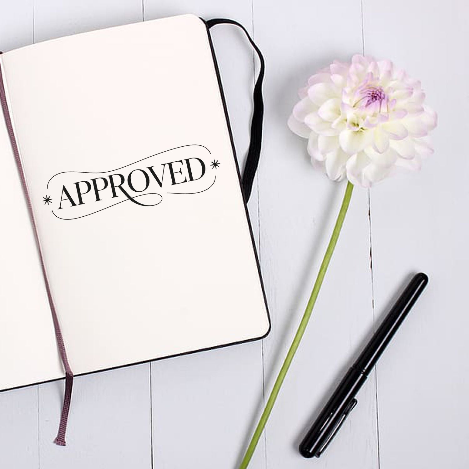 Approved rubber stamp imprint on notebook page with pen and flower, ideal for office document approval stamps.