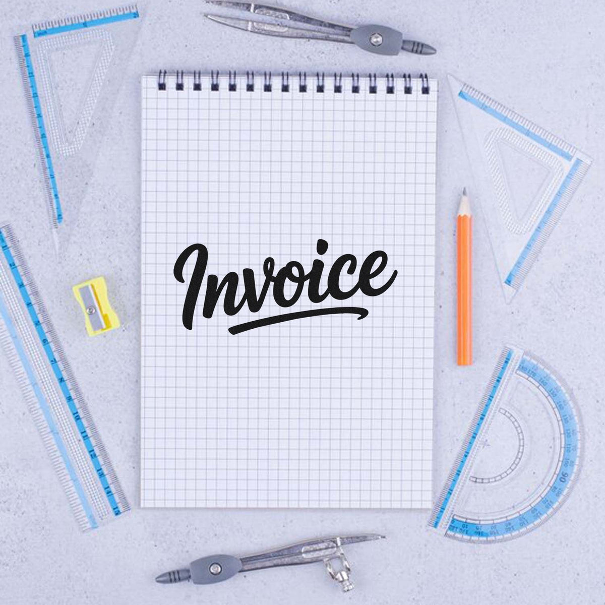 Invoice rubber stamp design on a graph notebook, surrounded by drafting tools for office, accounting, and bookkeeping use.