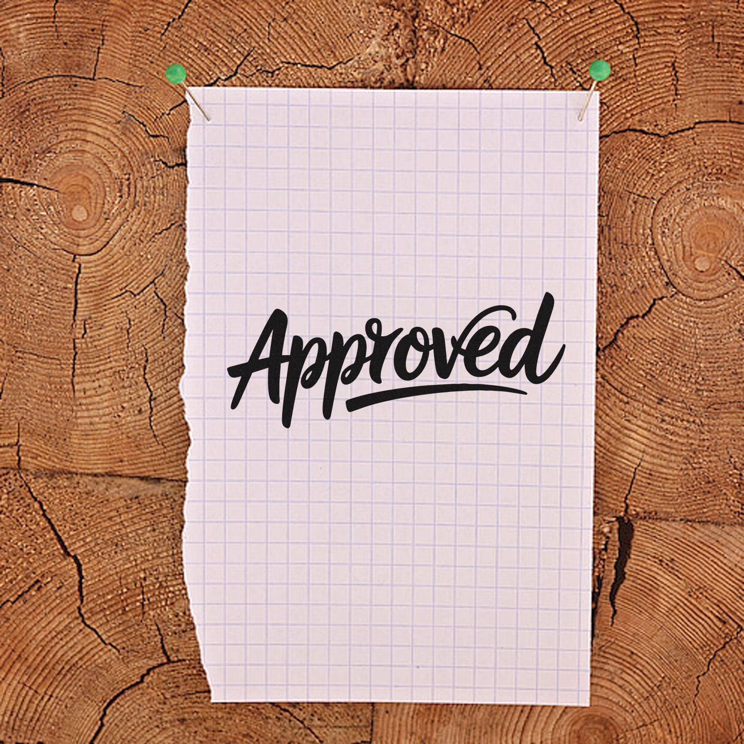 Approved rubber stamp on pinned graph paper over rustic wood background