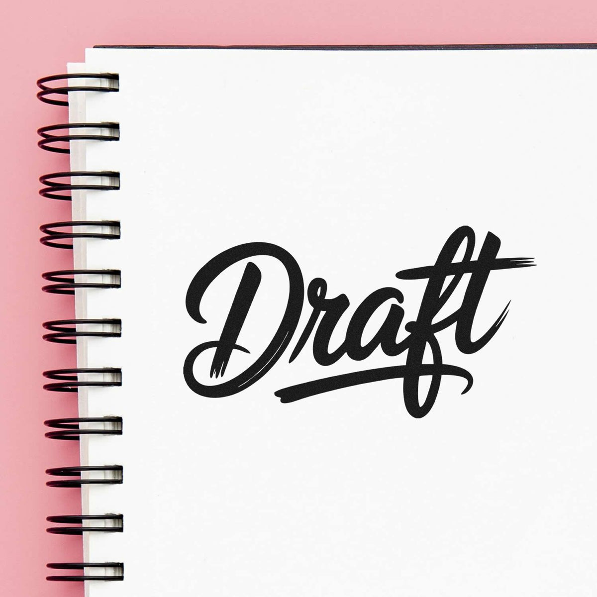 Draft rubber stamp on notebook page for marking documents, notes, and work-in-progress projects.