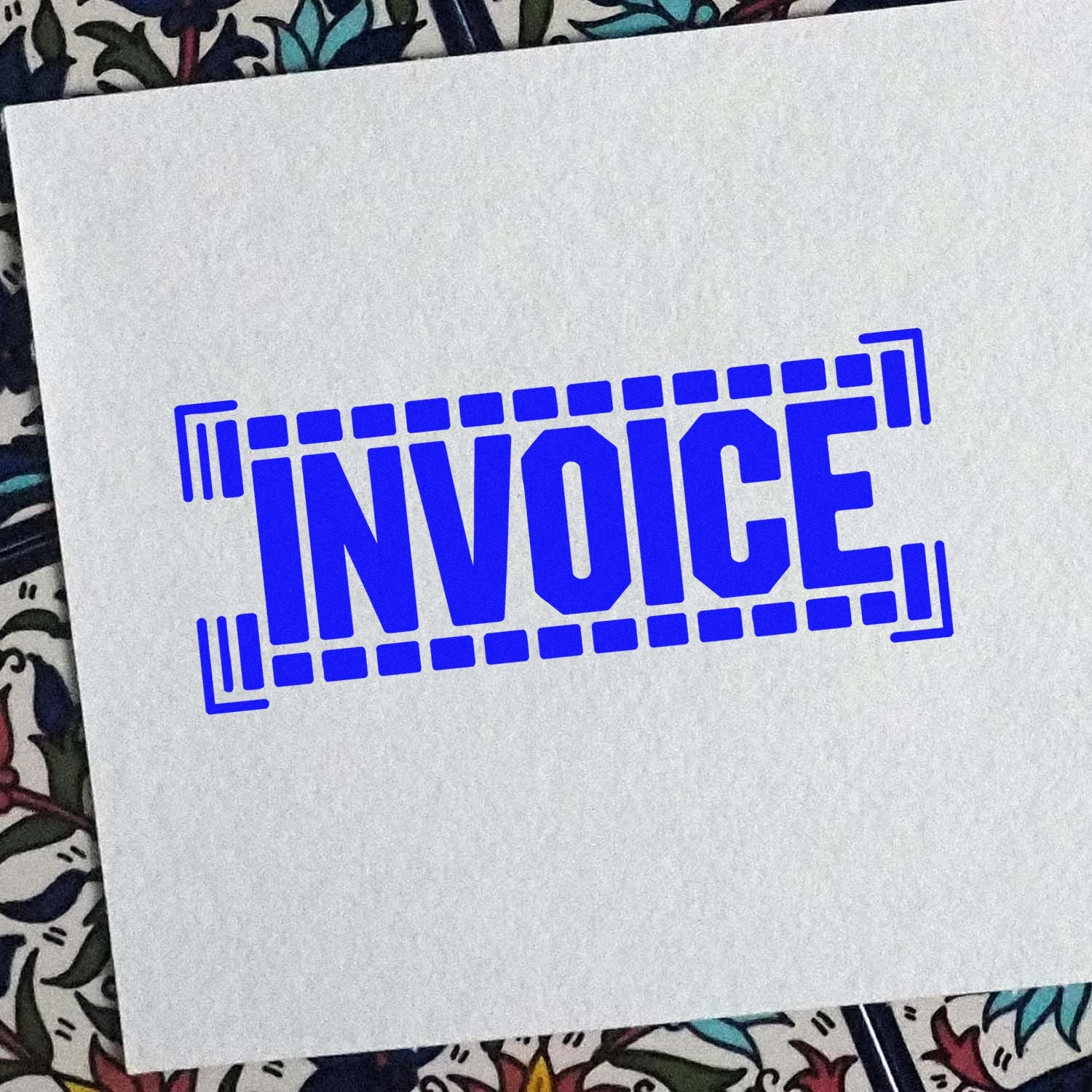 Blue invoice rubber stamp impression on paper for business billing and document processing.