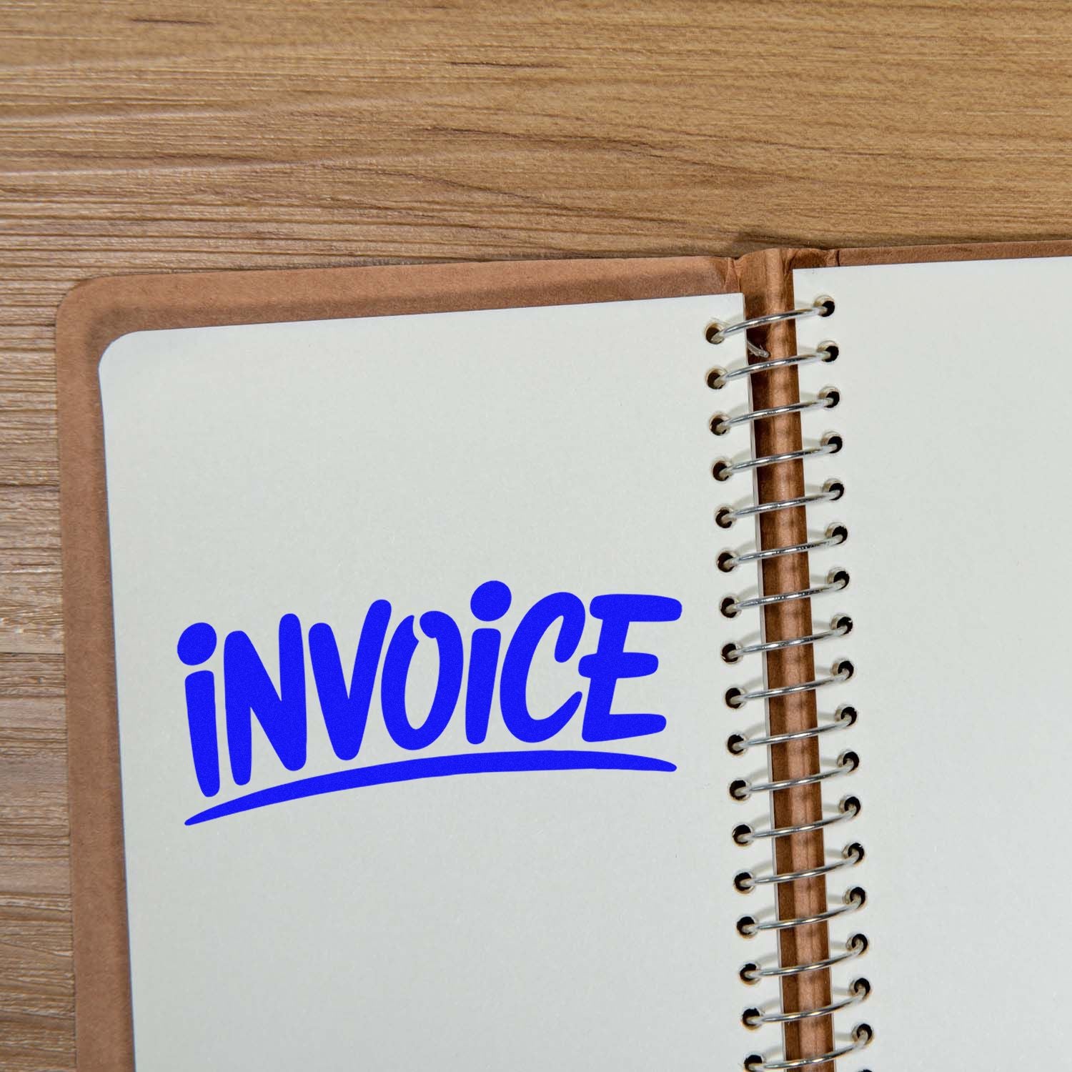 Blue invoice rubber stamp imprint on an open spiral notebook, ideal for office bookkeeping and document organization.