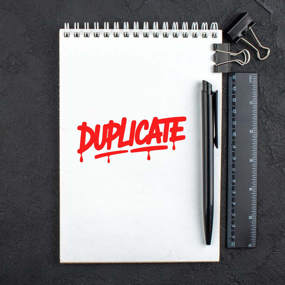 Red DUPLICATE rubber stamp impression on a notebook page, ideal for document marking, office use, and filing.