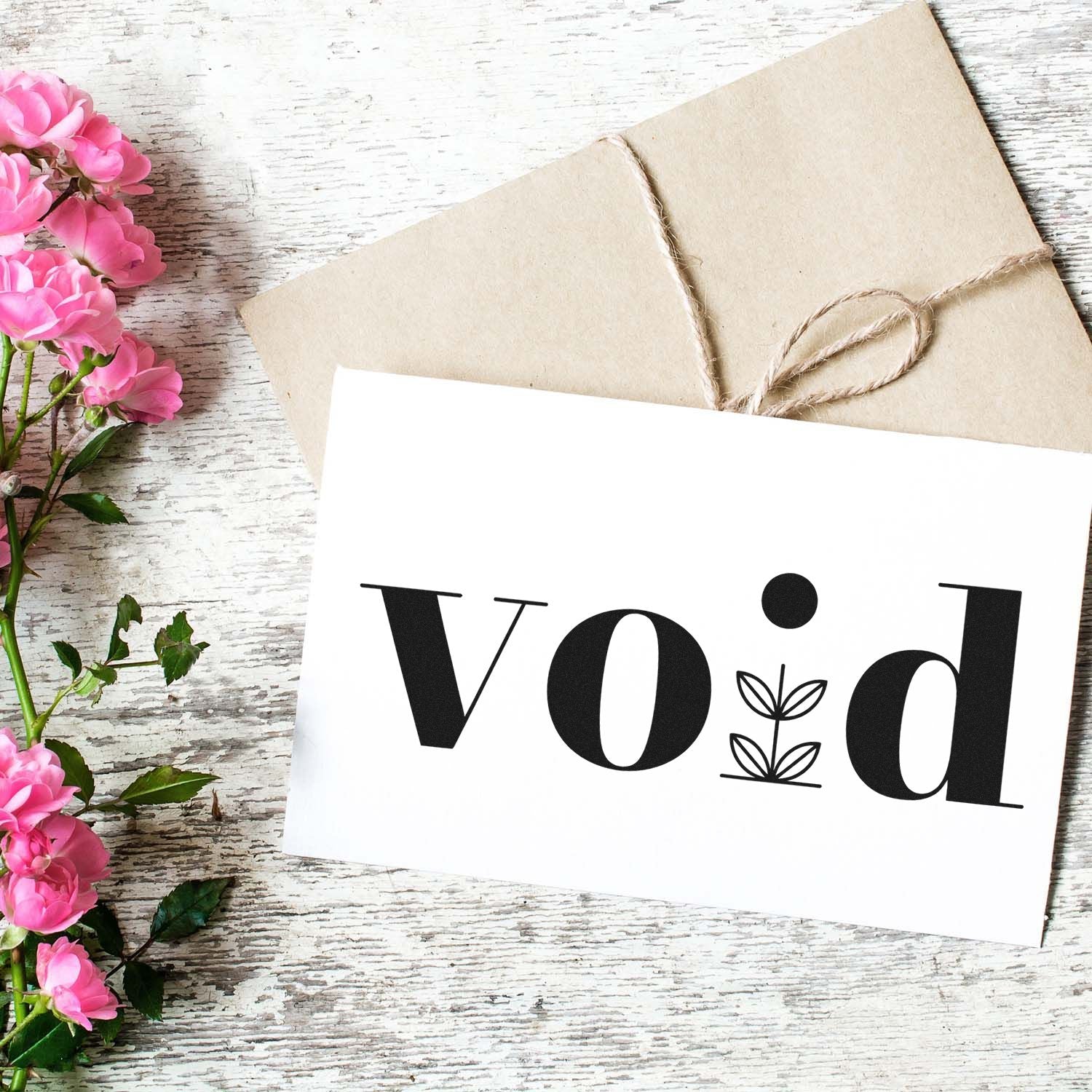 Void rubber stamp on white stationery with kraft envelope and pink flowers, perfect for handmade packaging and craft branding.