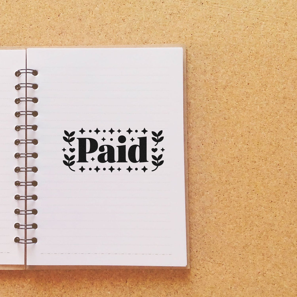 Decorative Paid rubber stamp impression on notebook page for invoice and bookkeeping tracking.