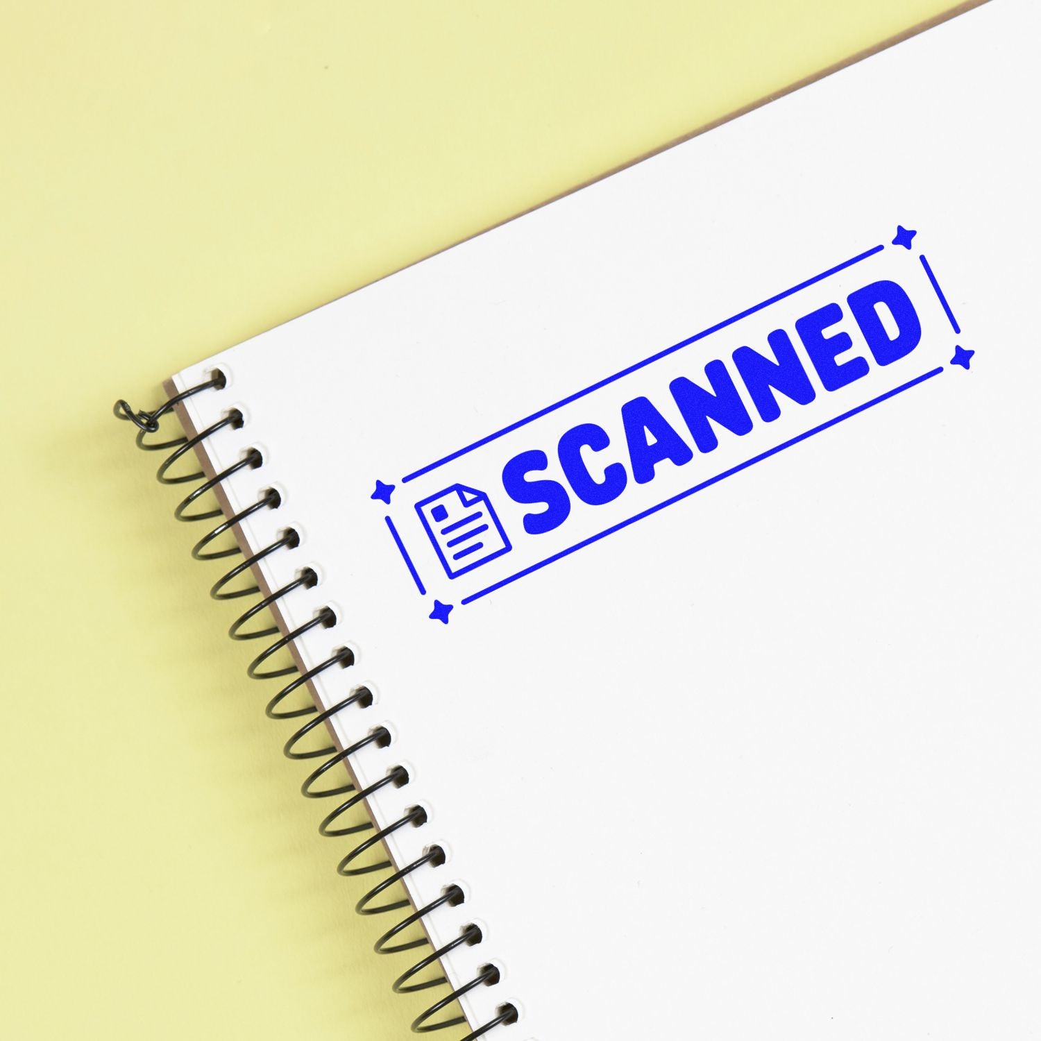 Blue scanned rubber stamp on a spiral notebook, marking a document as scanned and digitized.