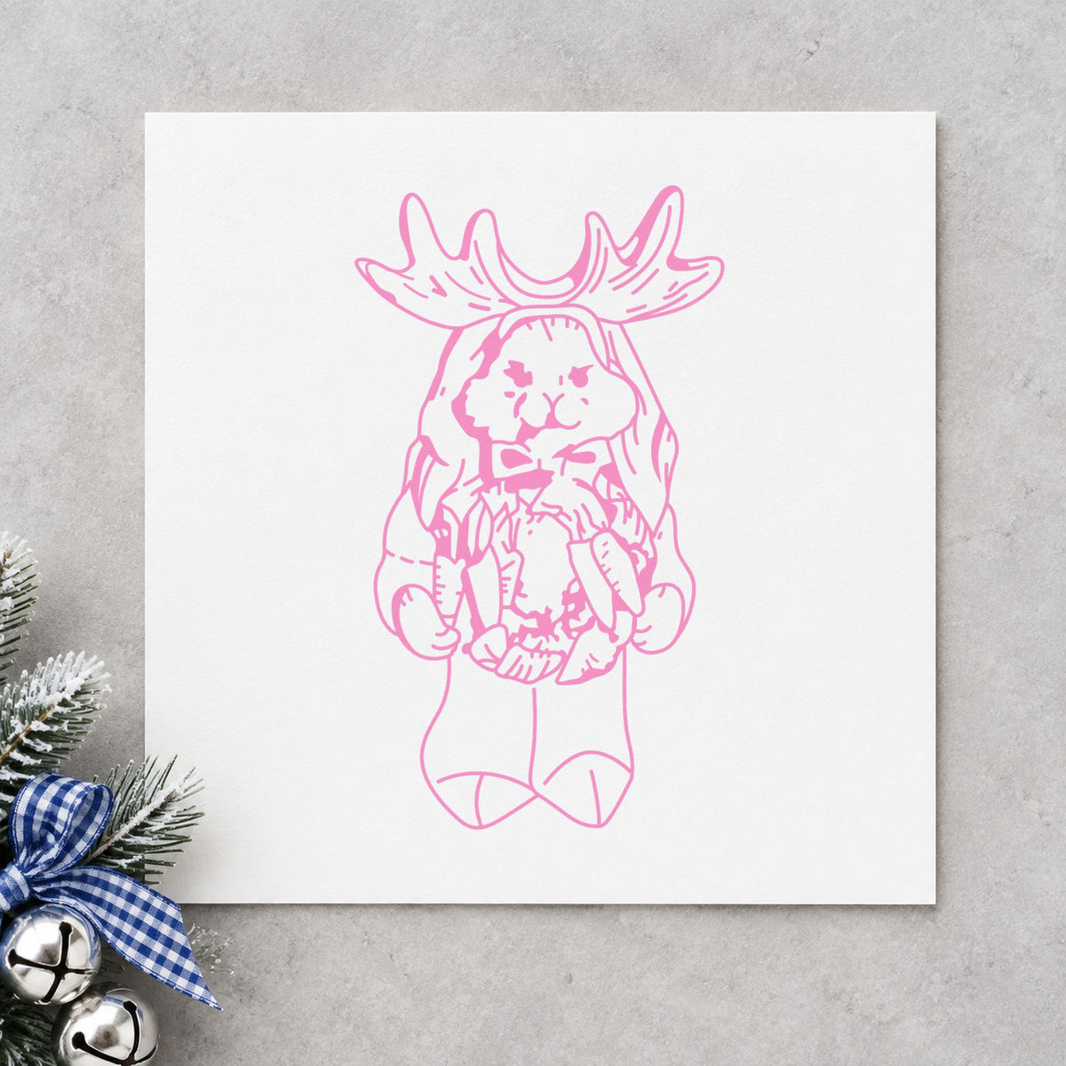 Bunny in Reindeer Costume Rubber Stamp impression in pink ink on white paper in a styled craft setting.