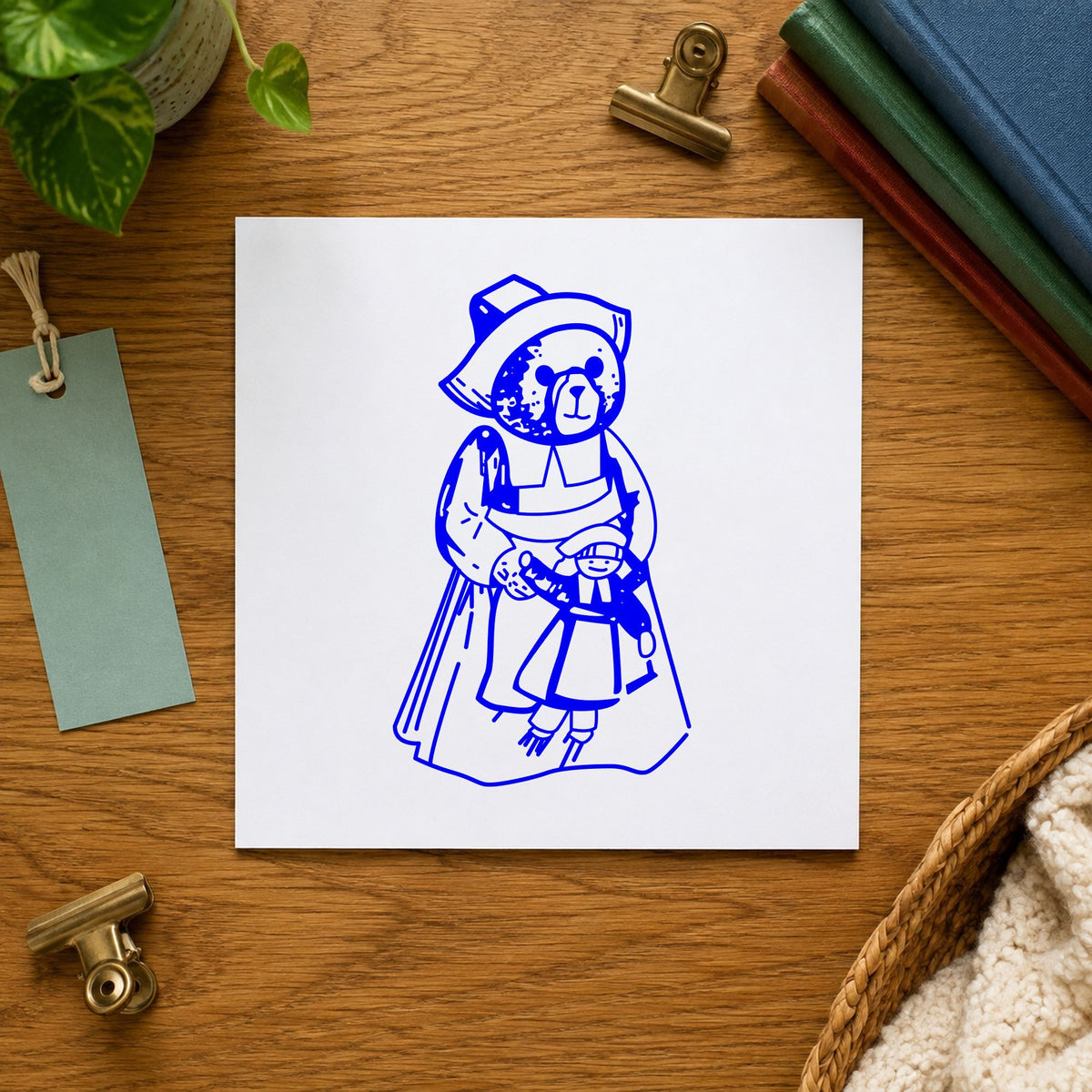 Girl Pilgrim Bear with Doll Rubber Stamp impression in blue ink on white paper in a styled craft setting.