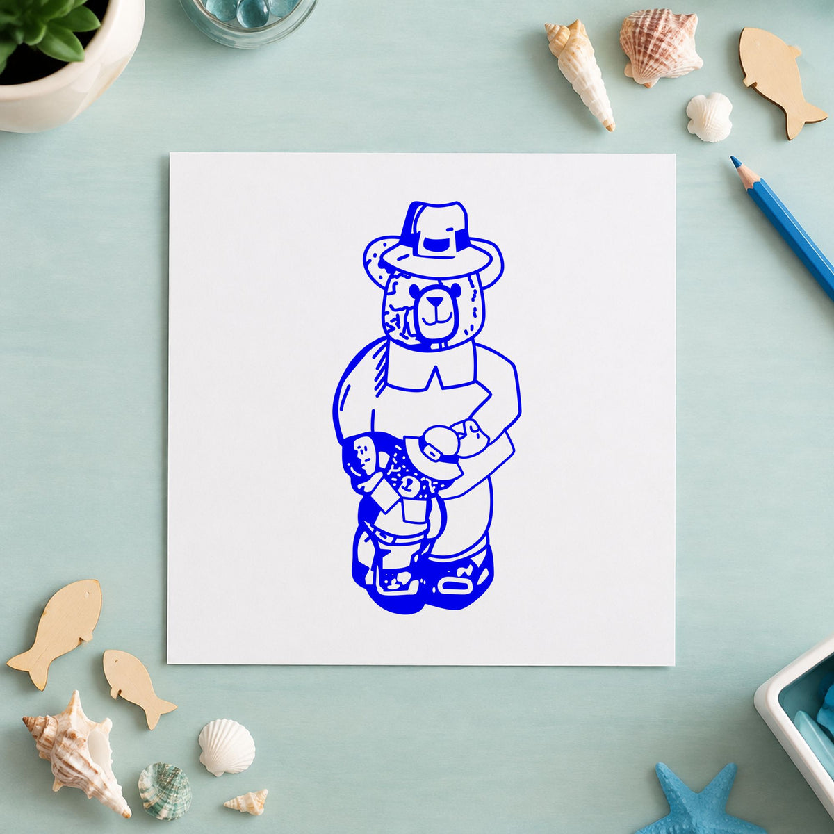 Boy Pilgrim Bear with Teddy Rubber Stamp impression in blue ink on white paper in a styled craft setting.