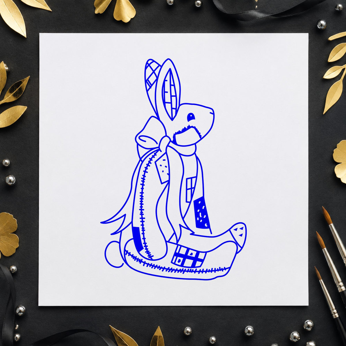 Blue patchwork craft stamp impression featuring the patchwork bunny with bow design on white paper.
