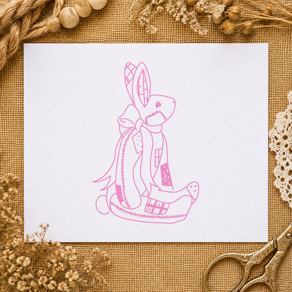 Patchwork Bunny with Bow Rubber Stamp impression in pink ink on white paper in a styled craft setting.