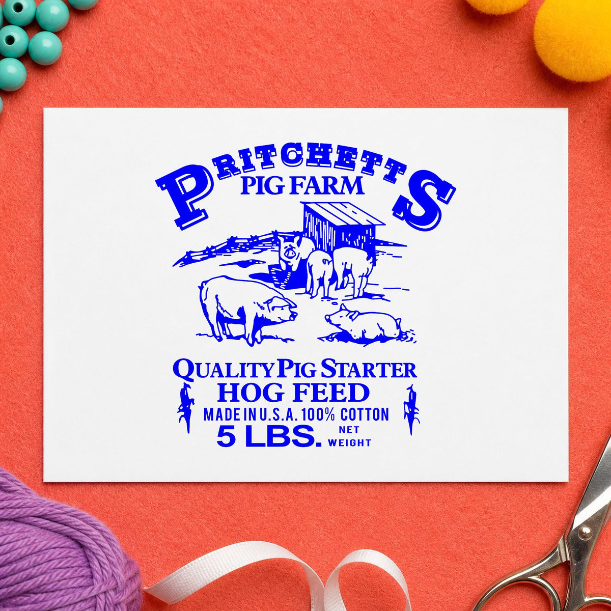 Hog Feed Label Rubber Stamp impression in blue ink on white paper in a styled craft setting.