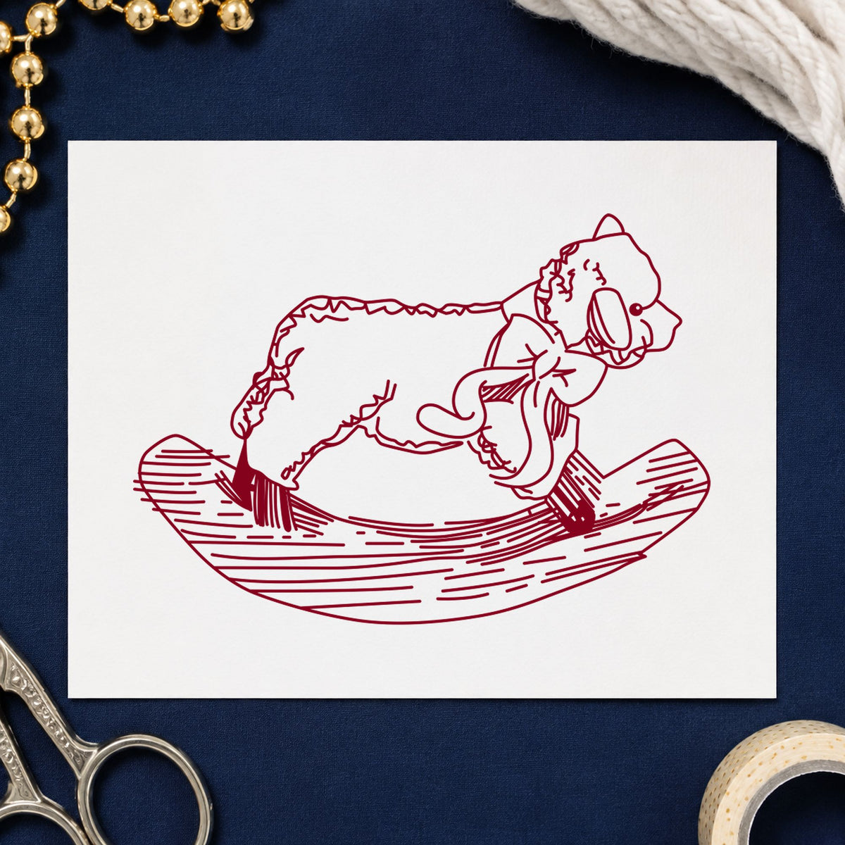 Rocking Sheep Rubber Stamp impression in burgundy ink on white paper in a styled craft setting.