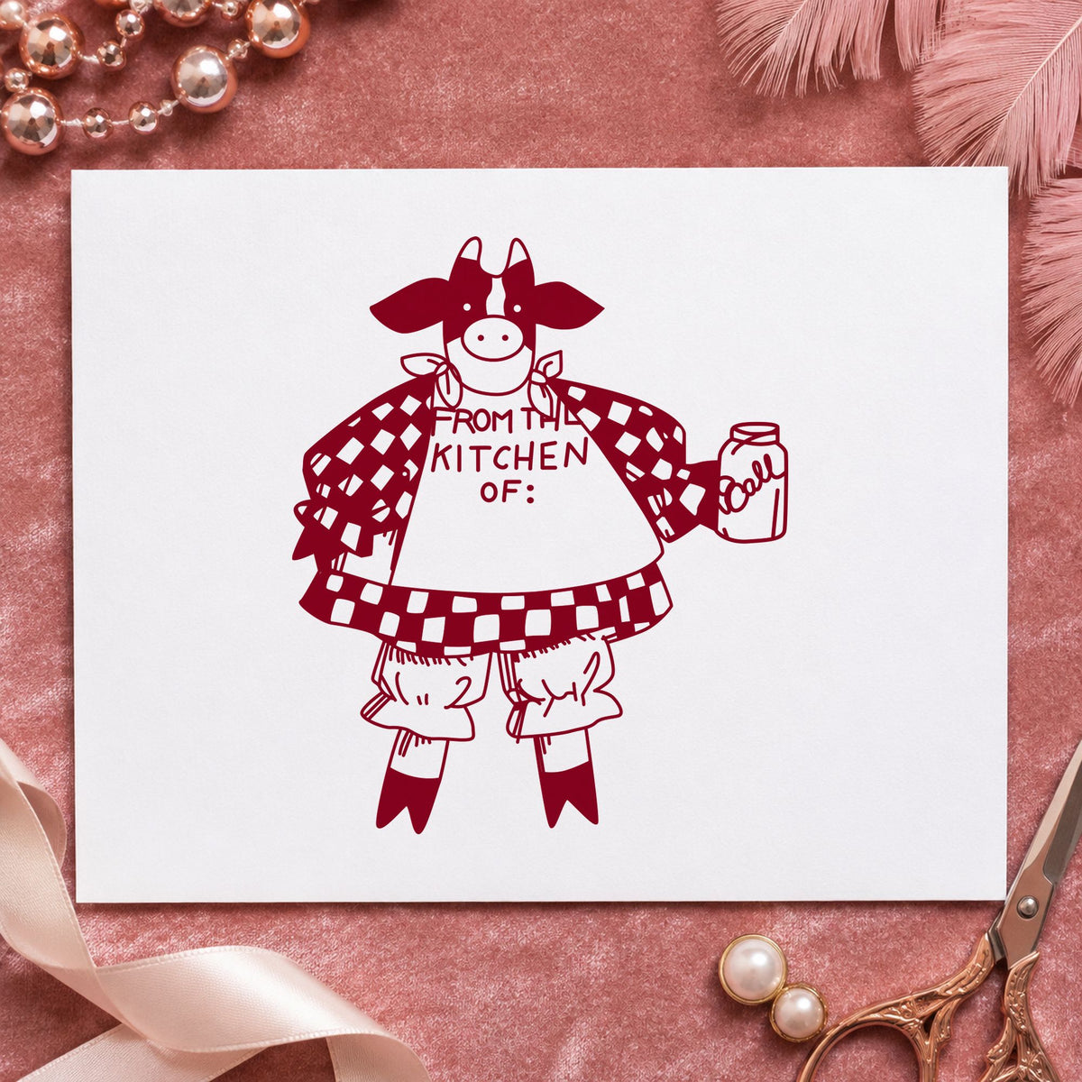 From the Kitchen Of Cow Rubber Stamp impression in burgundy ink on white paper in a styled craft setting.