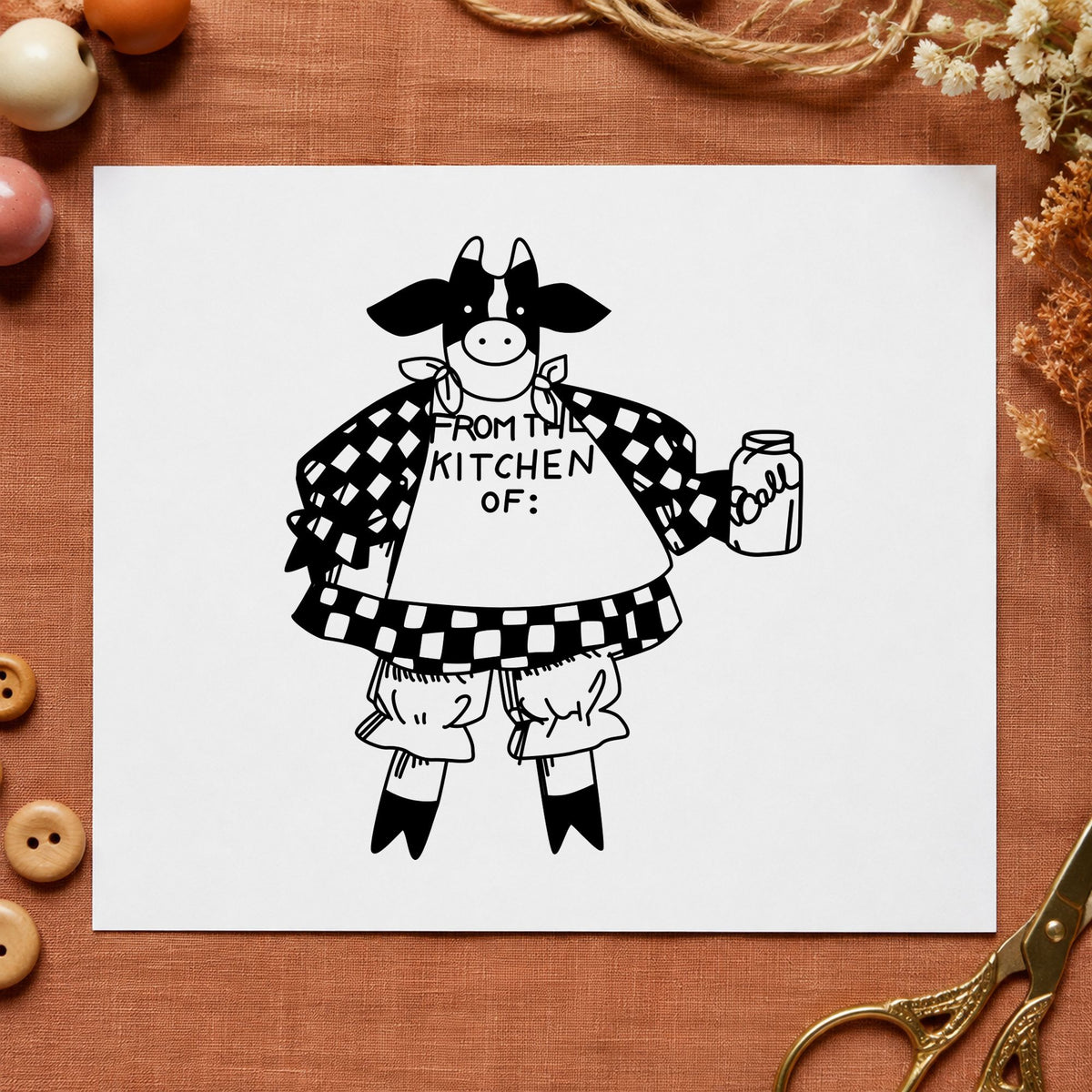 Black impression from a kitchen rubber stamp, featuring the from the kitchen of cow design on white paper.