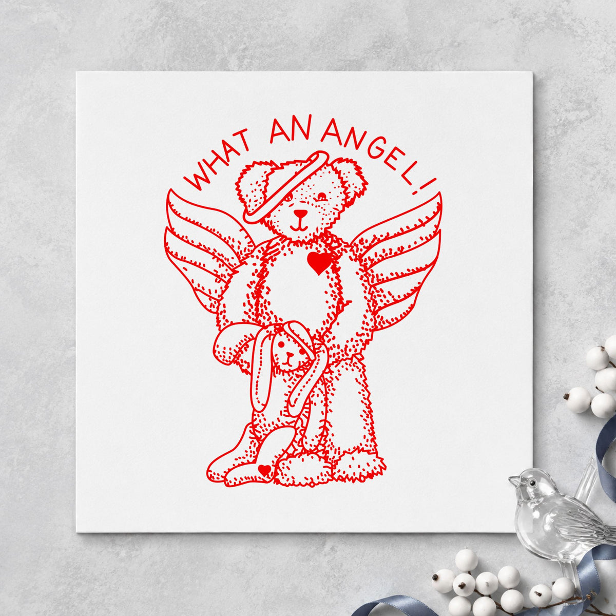 What an Angel Bear and Bunny Rubber Stamp impression in red ink on white paper in a styled craft setting.