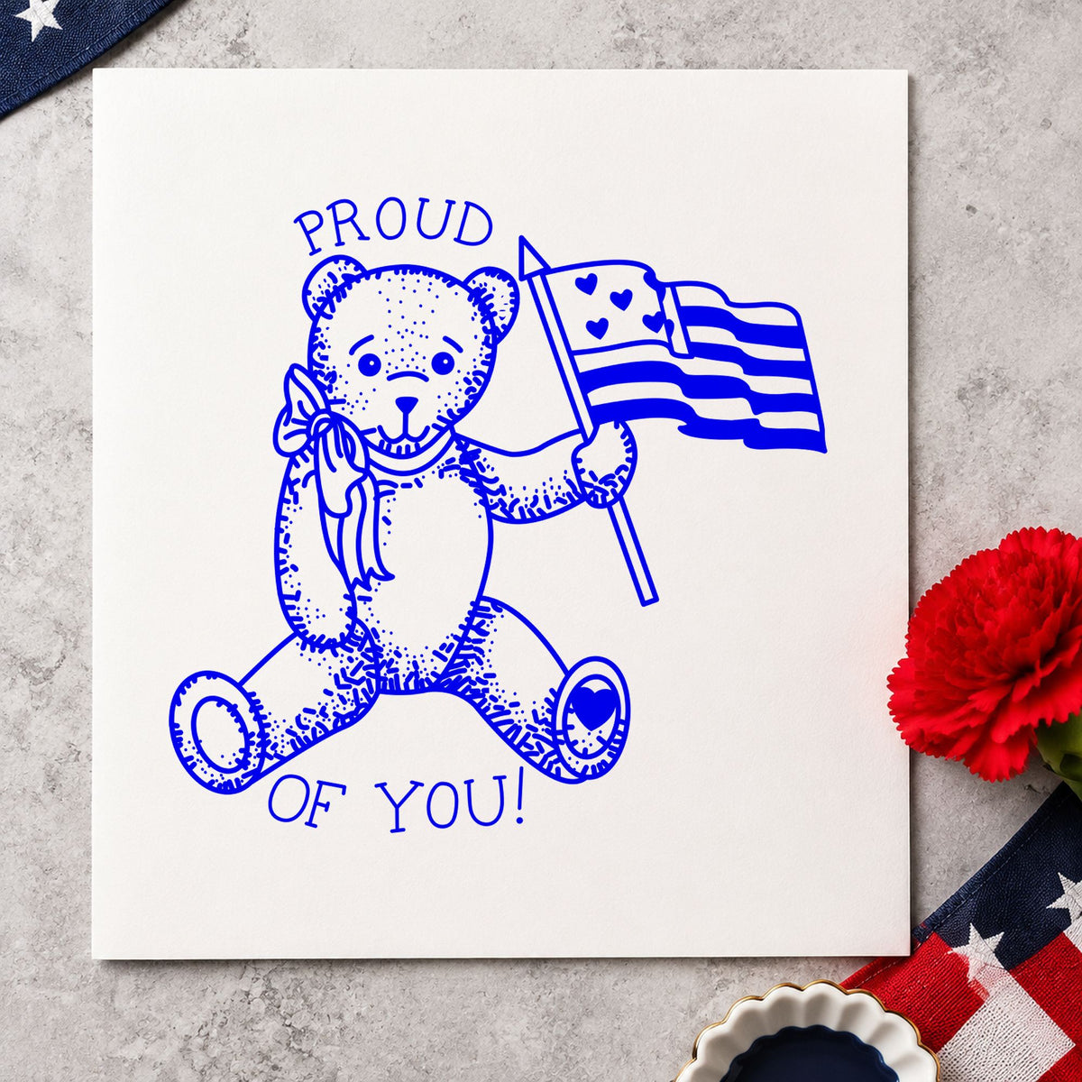 Blue celebration card stamp impression featuring the proud of you flag bear small design on white paper.