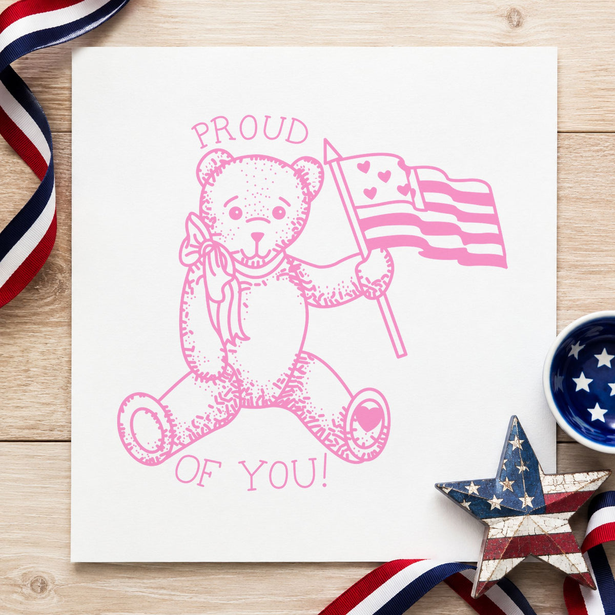 Proud of You Flag Bear Rubber Stamp Small impression in pink ink on white paper in a styled craft setting.
