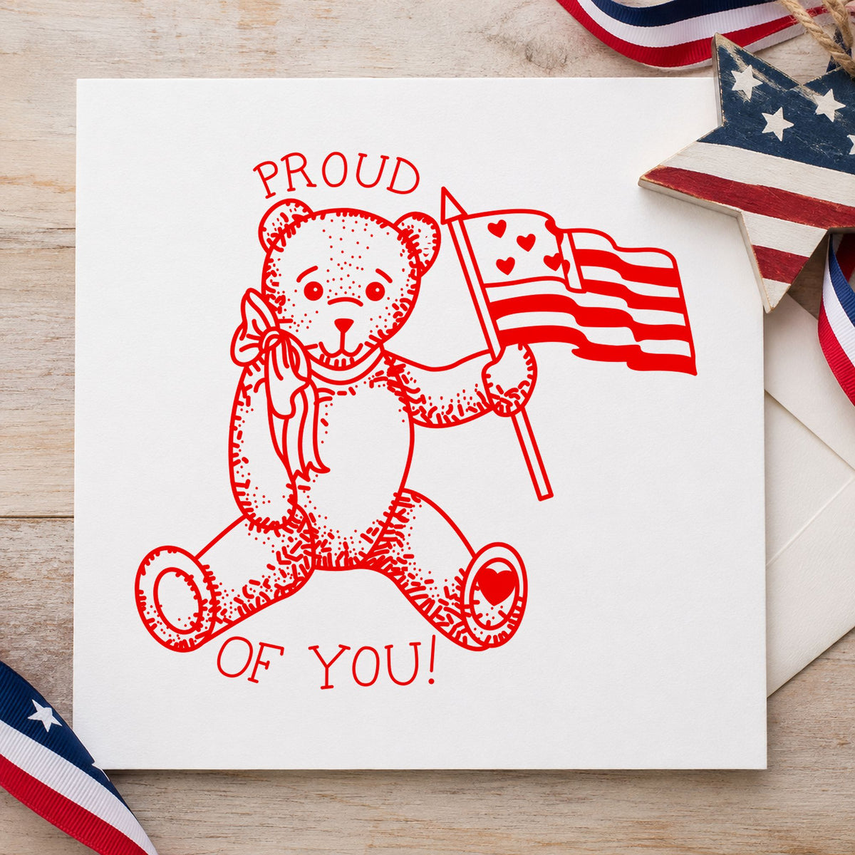 Proud of You Flag Bear Rubber Stamp Small impression in red ink on white paper in a styled craft setting.