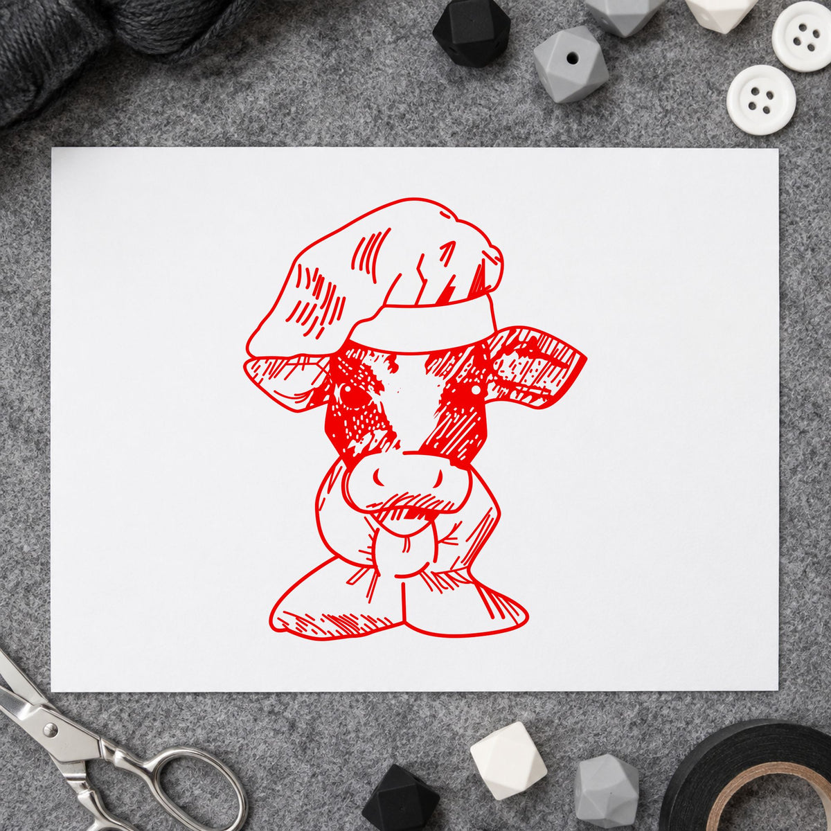 Chef Cow Portrait Rubber Stamp impression in red ink on white paper in a styled craft setting.