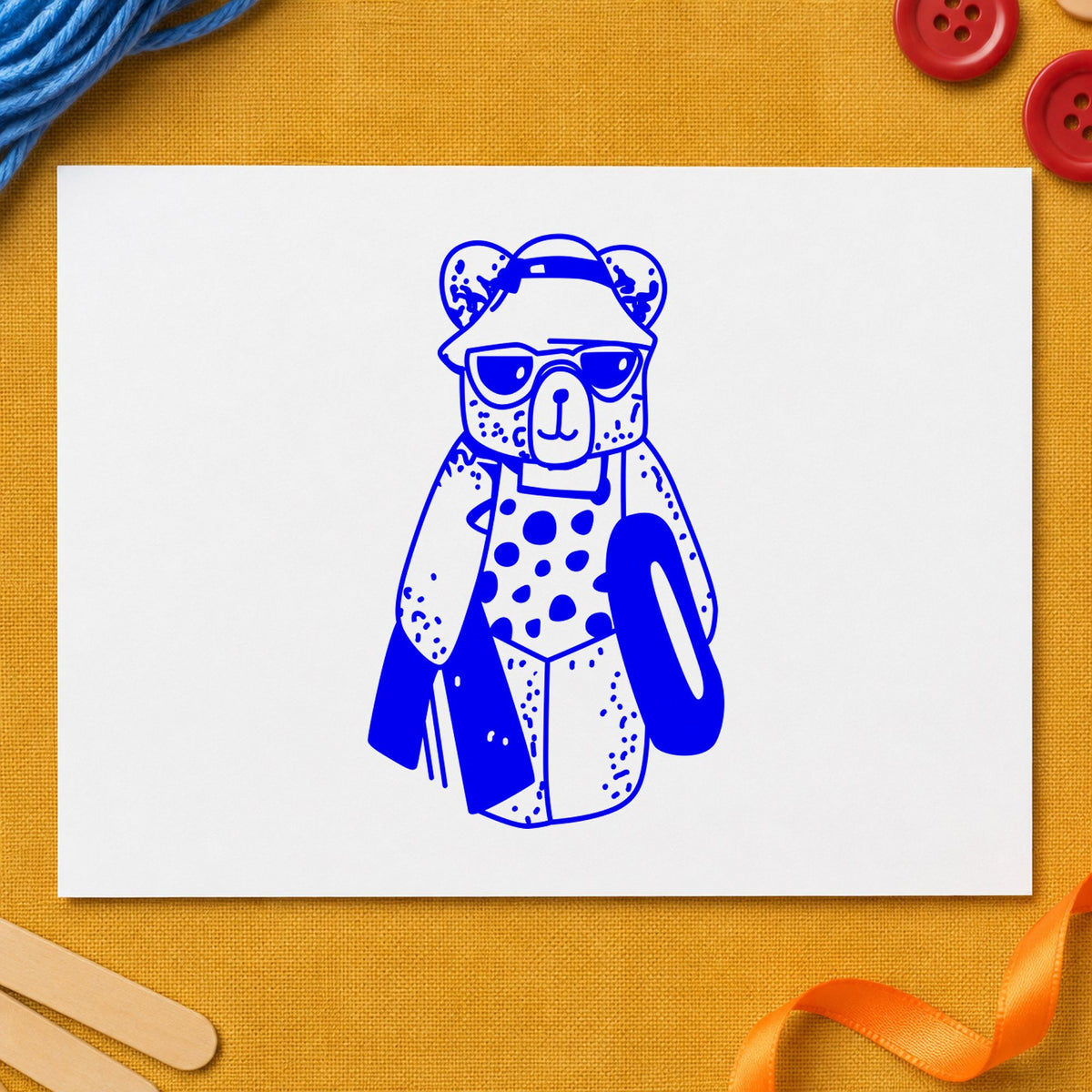 Blue summer vacation stamp impression featuring the bear with inner tube design on white paper.
