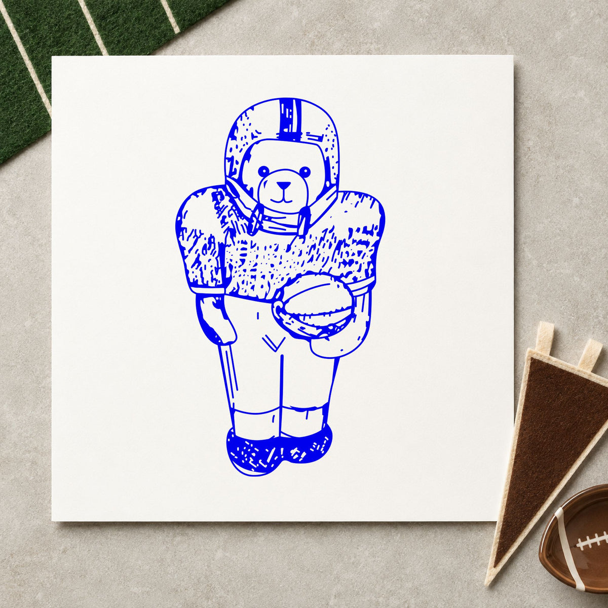 Blue sports scrapbook stamp impression featuring the football bear in uniform design on white paper.